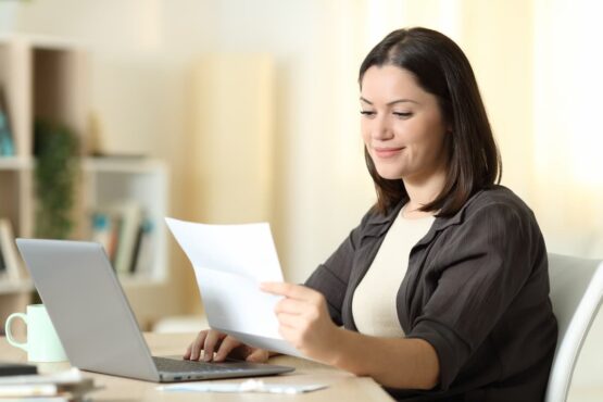 Mulher observando uma carta de apresentação sentada em uma mesa de escritório na frente do computador