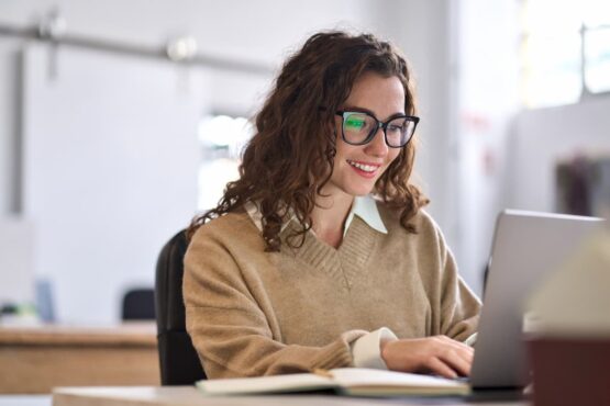 Imagem de uma mulher usando o computador sorrindo