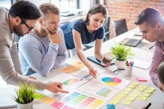 Grupo fazendo estratégias de organização no seu ambiente de trabalho em uma mesa branca com post-it