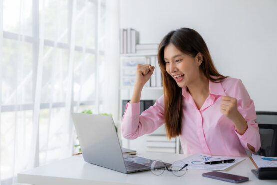 Imagem de mulher comemorando na frente do seu computador no escritório