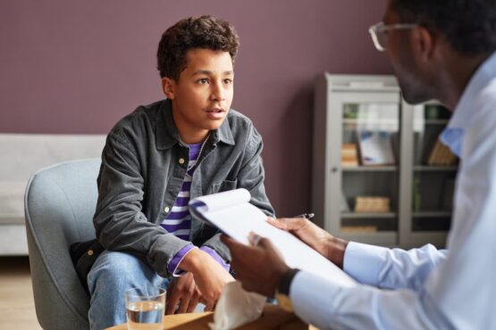 Imagem de um jovem em uma entrevista de emprego com o recrutador segurando seu currículo