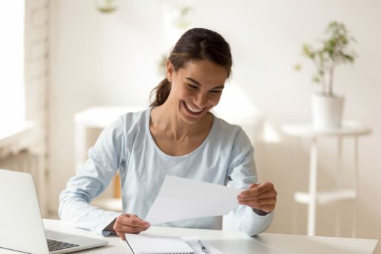 Imagem de uma mulher sorrindo olhando para um papel