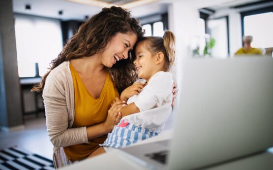 Imagem de uma mulher brincando com uma criança no colo no escritório