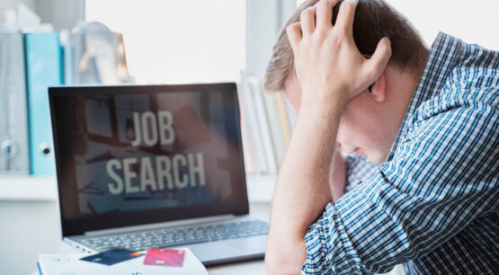 Rapaz sentado em frente ao computador com as mãos na cabeça, após sofrer um golpe